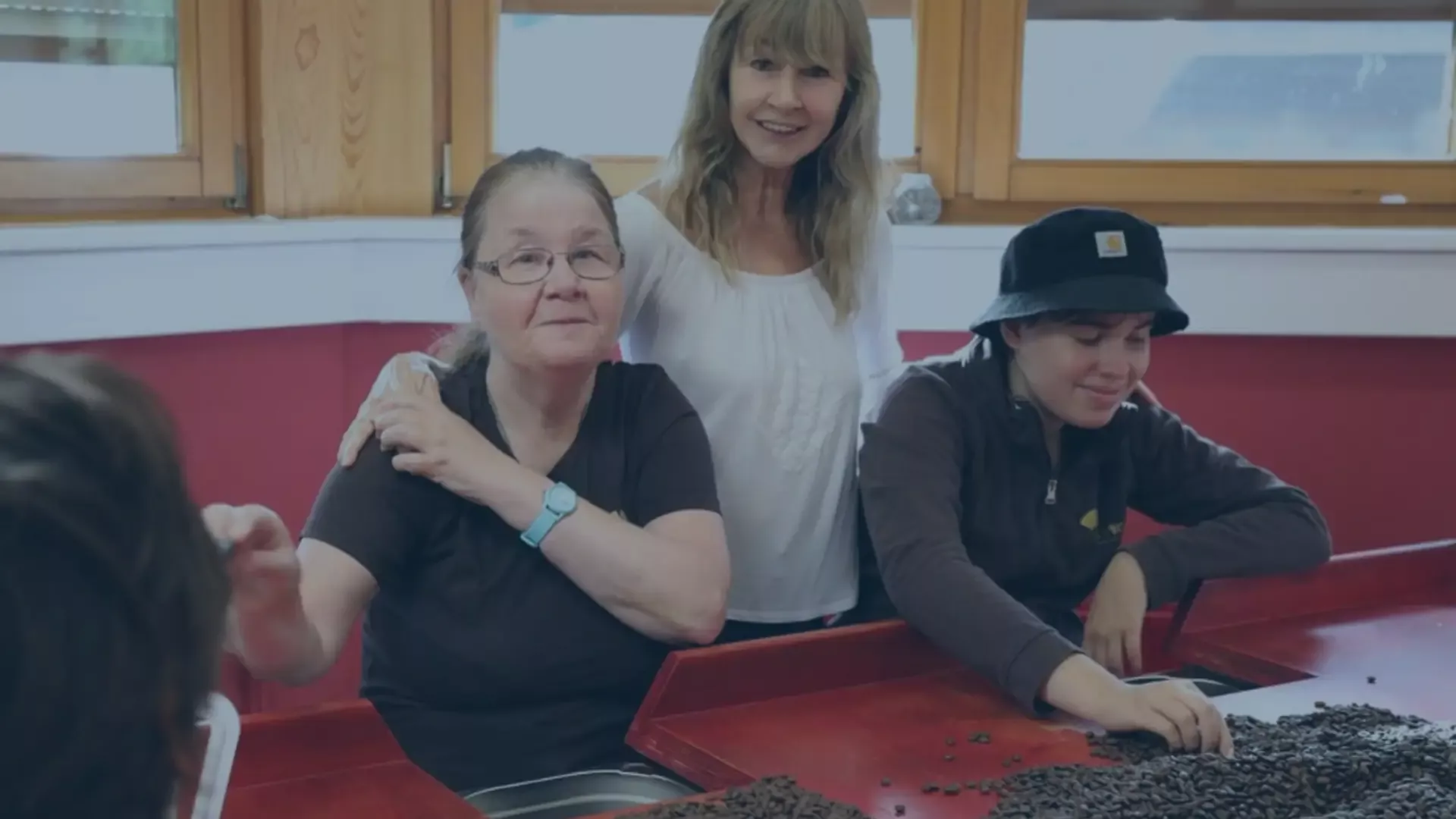 Drei Personen in der Rösterei Laufenmühle sortieren gemeinsam Kaffeebohnen – ein Symbol für Nachhaltigkeit, Inklusion und verantwortungsvollen Kaffeegenuss bei audius.