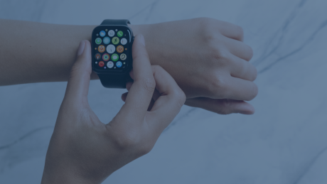 Eine Person trägt eine Apple Watch am Handgelenk und bedient sie mit der anderen Hand. Das Display der Smartwatch zeigt die App-Übersicht mit verschiedenen Symbolen. die Verwaltung über Mobile Device Management (MDM), Organisation durch Kalender- und Aufgaben-Apps, schnelle Kommunikation, Gesundheitsüberwachung sowie Sicherheitsfunktionen wie Notrufe und Standortfreigabe. Zudem wird ihre Integration in Unternehmensprozesse und ihre Rolle bei der Steigerung von Produktivität und Sicherheit betont.