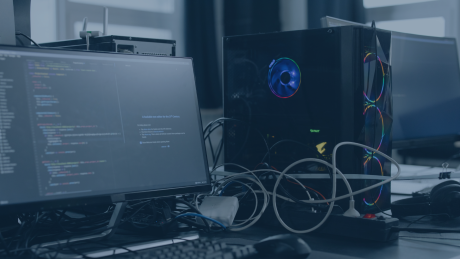 Cloud als Produkt – Platform Engineering mit AWS Landing Zone | audius Arbeitsumgebung mit Monitoren und einem Desktop-PC mit leuchtenden Lüftern; auf dem Bildschirm ist Programmcode zu sehen – Symbolbild für moderne Cloud- und DevOps-Umgebungen, Infrastructure-as-Code und automatisierte Plattformentwicklung im Rahmen des Platform Engineerings und der AWS Landing Zone.